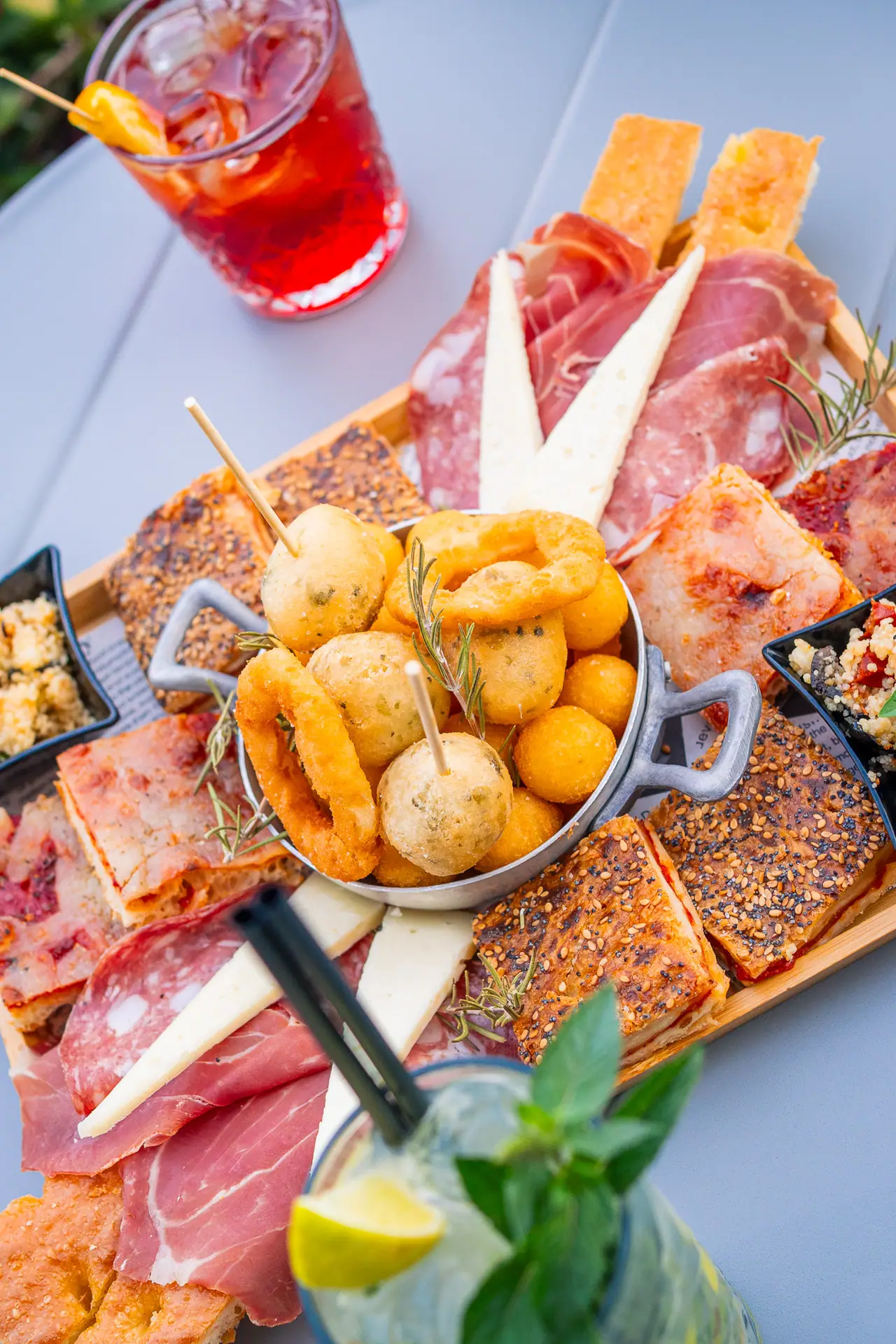Aperitivo nel dehors: spritz e tagliere sul tavolo bianco tra le piante
