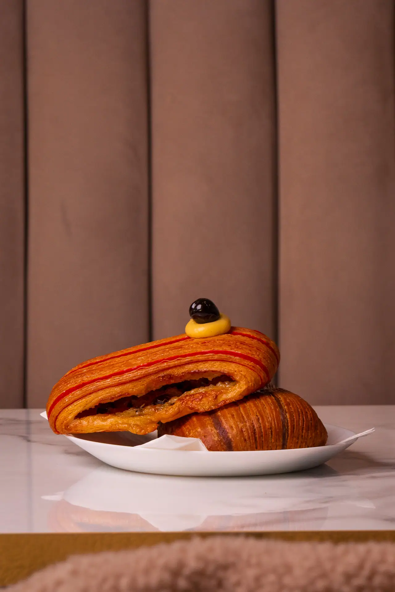 Pain suisse con crema e gocce di cioccolato sul piatto, divanetto in velluto
