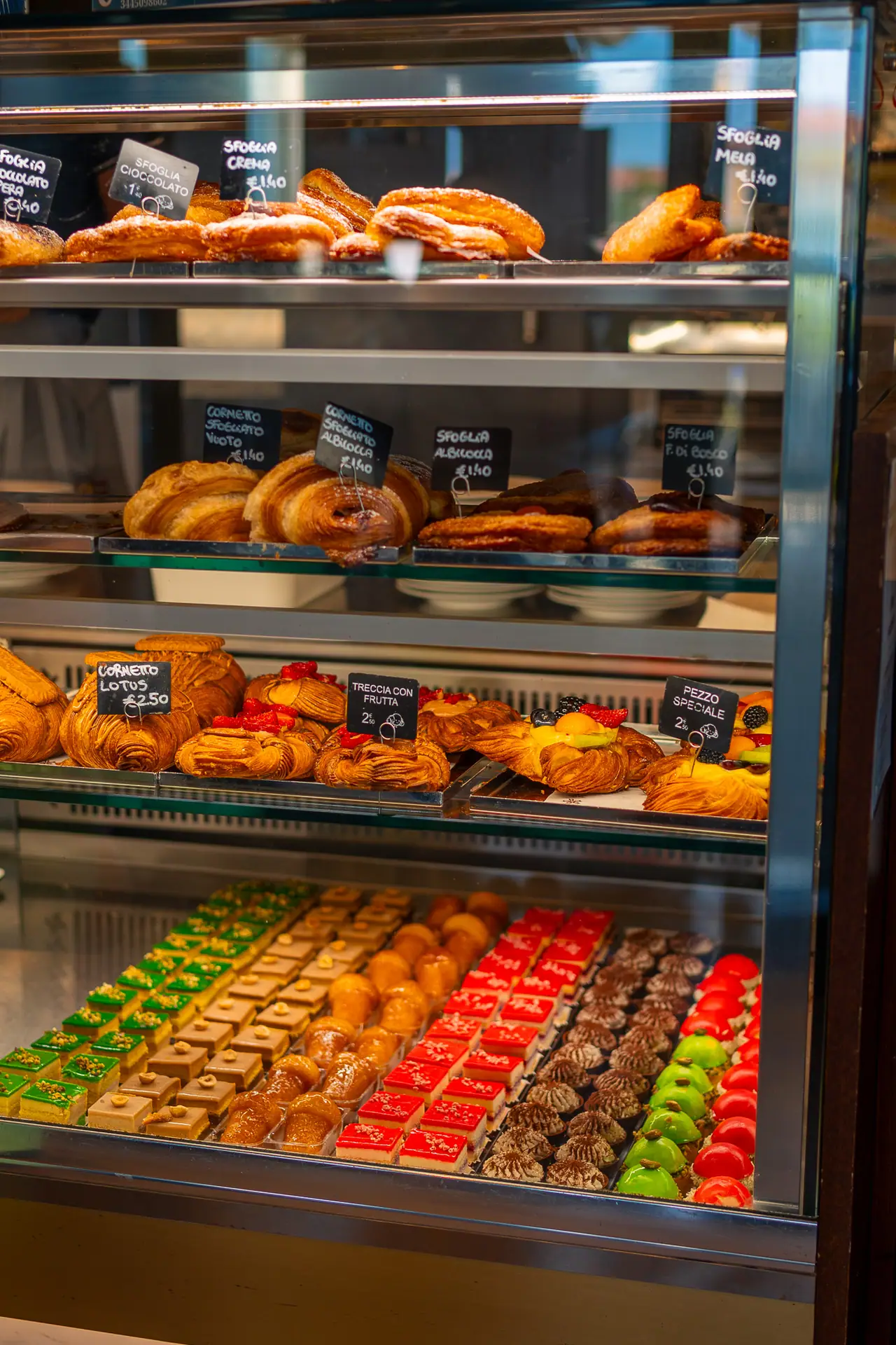 La vetrina della pasticceria piena di mignon, cornetti e torte
